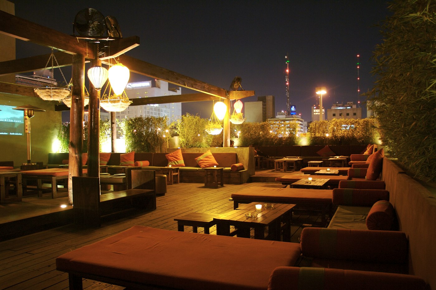 An elegant rooftop lounge at dusk, overlooking the city skyline.